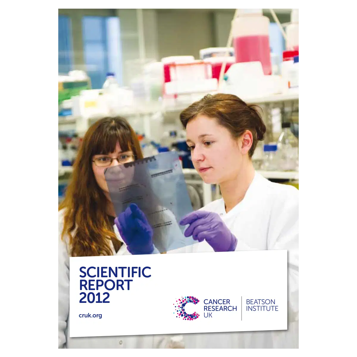 Two scientists in lab coats and gloves examine a transparent sheet of research data in a laboratory filled with bottles and equipment. The image is the cover of the Scientific Report 2012 from Cancer Research UK Beatson Institute.