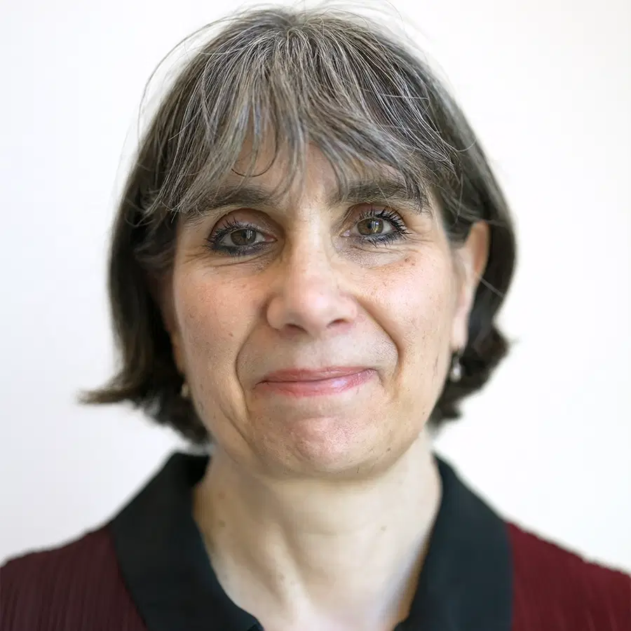 cruk-scotland-institute-karen-blyth A middle-aged woman with short grey hair and light skin smiles gently at the camera. She is wearing a collared top. The background is plain and light.