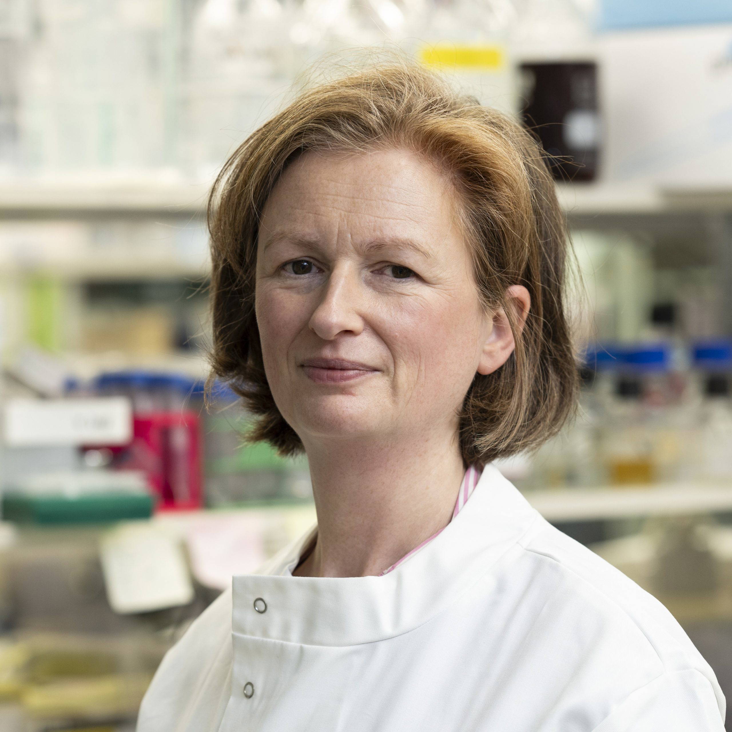 A woman in a white lab coat standing in a laboratory.